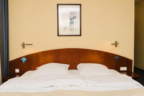 a bed with a wooden headboard and a picture on the wall at Hotel Rezydencja Solei in Poznań
