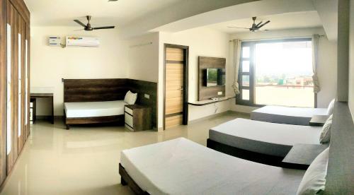 a bedroom with three beds and a television in it at Pride Home in Chandīgarh
