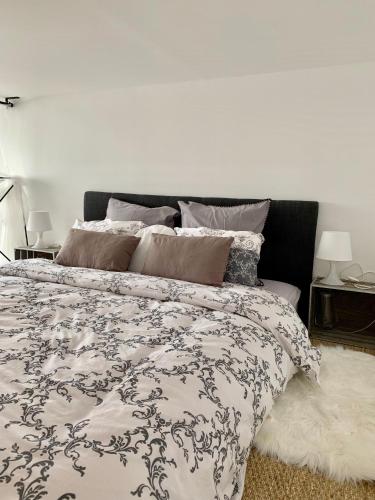 - un lit avec une couette et des oreillers en noir et blanc dans l'établissement Mini-loft, Clos des Arts - parking gratuit, à Avignon