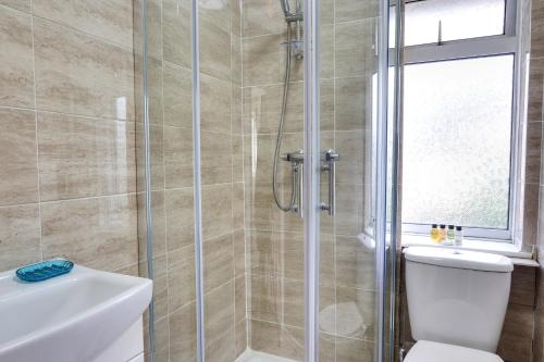 a bathroom with a shower with a toilet and a sink at Clarence Place in Edgware