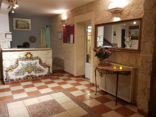 een kamer met een spiegel en een tafel met bloemen bij Hôtel-Restaurant le Commerce in Nogaro