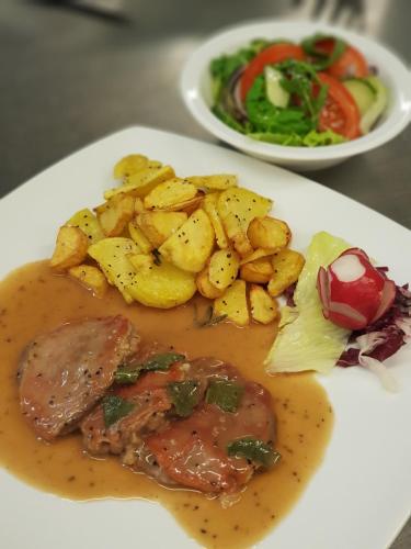 a plate of food with meat and potatoes and a salad at Toscana Restaurant and Bed & Breakfast in Padborg