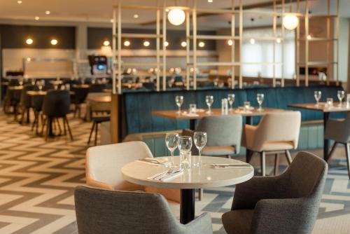 un restaurante con mesas y sillas y copas de vino en The Hoban Hotel Kilkenny en Kilkenny