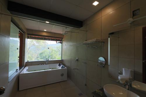 a bathroom with a tub and a sink and a window at Petals Resorts Wayanad in Tariyod