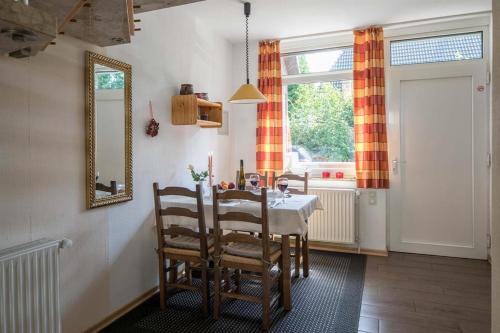 ein Esszimmer mit einem Tisch, Stühlen und einem Spiegel in der Unterkunft Ferienhaus "An der Bäke" in Bad Zwischenahn