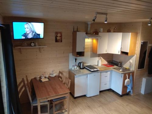 a kitchen with a table and a tv on the wall at Leśny Zakątek Sztutowo in Sztutowo