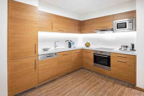 a kitchen with wooden cabinets and a microwave at Radisson Blu Hotel & Residence, Riyadh Diplomatic Quarter in Riyadh