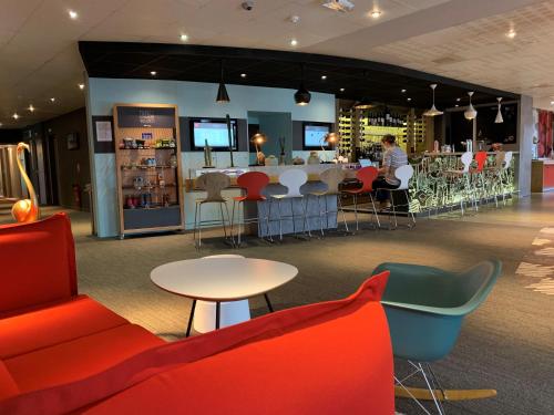 a restaurant with chairs and tables and a bar at ibis Honfleur in Honfleur
