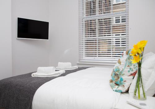a white bedroom with a bed and a window at Soho Suites by Indigo Flats in London