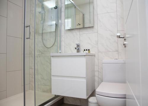un bagno bianco con doccia e WC di Soho Suites by Indigo Flats a Londra