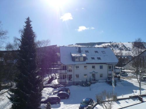 a large white house in the snow with parked cars at Fewo C am Kurpark mit MeineCardPlus in Willingen