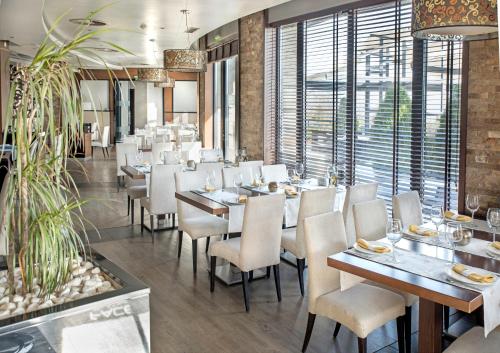 a dining room with tables and chairs and windows at Face Hotel in Sofia