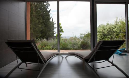 two chairs sitting in a room with large windows at Mas Ses Vinyes - Adults Only in Begur