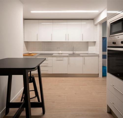 a kitchen with white cabinets and a black table at GORLIZ Apartment close to the BEACH & Parking in Górliz-Elexalde