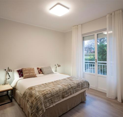 a white bedroom with a bed and a window at GORLIZ Apartment close to the BEACH & Parking in Górliz-Elexalde