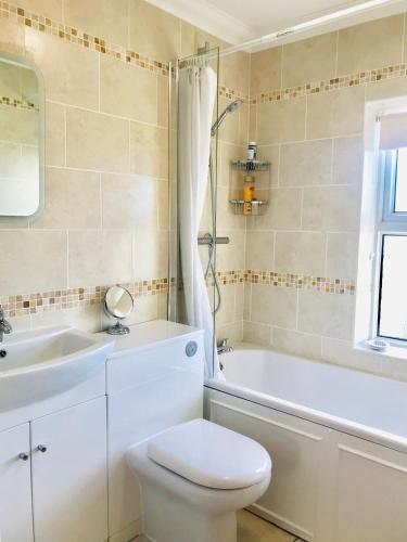 a bathroom with a toilet and a tub and a sink at Southgrove View, Family Holiday Cottage in Ventnor