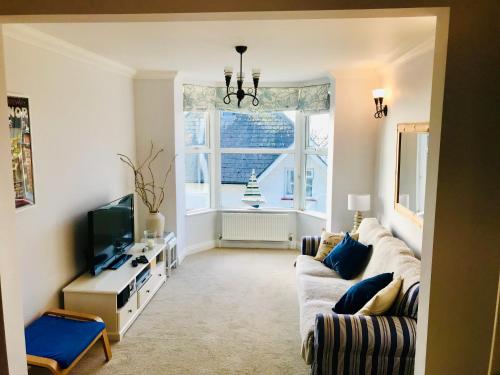 a living room with a couch and a tv and a window at Southgrove View, Family Holiday Cottage in Ventnor