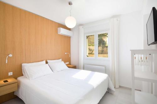 een slaapkamer met een wit bed en een televisie bij Seaview Luxurious Apartment near Corfu town by Konnect - Adults only in Corfu-stad