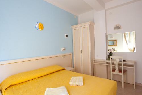 a bedroom with a yellow bed and a desk at Hotel Altair in Misano Adriatico