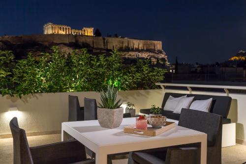a white table and chairs on a balcony at night at Divani Palace Acropolis in Athens