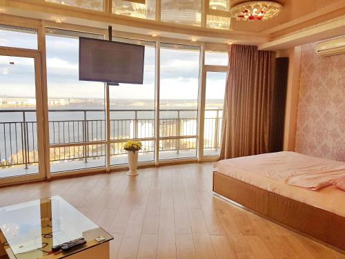 a bedroom with a bed and large windows with a tv at Most City Apart-Hotel in Dnipro