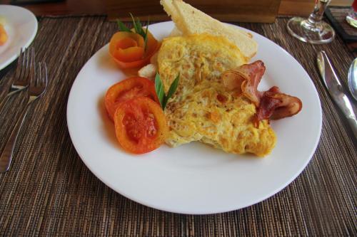 eine weiße Platte mit einem Omelett mit Speck und Tomaten in der Unterkunft The Penida Bungalow in Nusa Penida