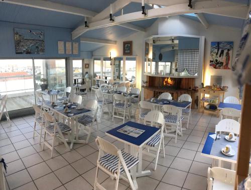 un restaurante con mesas blancas y sillas blancas en Hotel Bord A Bord, en Noirmoutier-en-l'Île