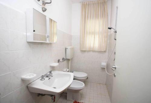 a white bathroom with a sink and a toilet at Residence Stella Polare in Bibione