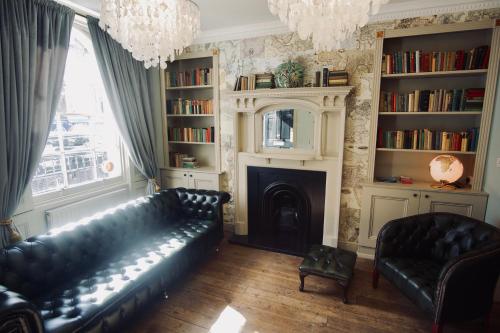 a living room with a black leather couch and a fireplace at Swinton Hotel in London