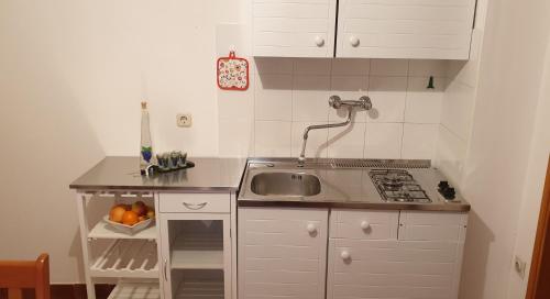 una pequeña cocina blanca con fregadero y fregadero en Sweet apartment in Pomer, en Pomer