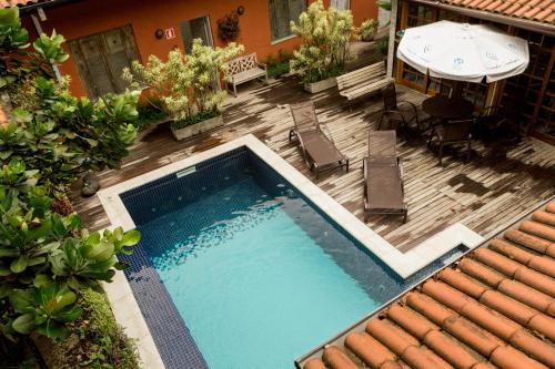 una terraza de madera con vistas a una piscina. en Pousada Camburi, en Camburi