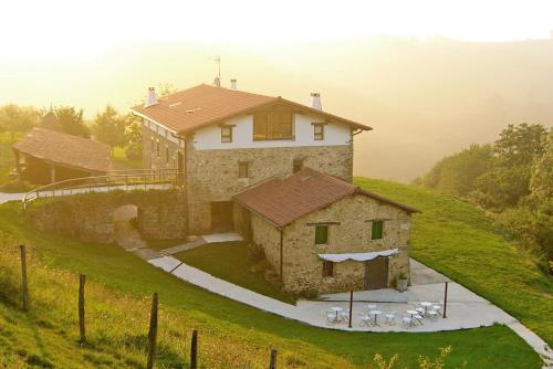 una casa grande en la cima de una colina verde en Mañarinegi Apartamentos Rurales, en Aia