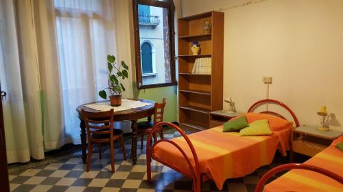 a room with two beds and a table and a table and chairs at Ostello Domus Civica in Venice