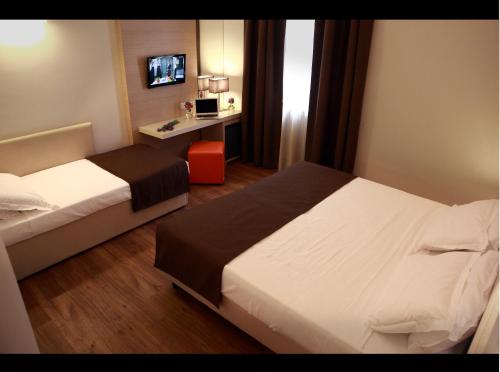 a hotel room with two beds and a desk at Hotel Colonne in San Giovanni Rotondo
