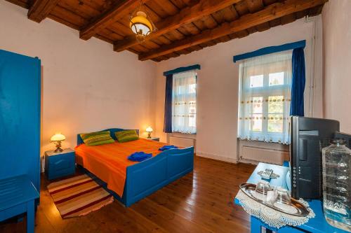 a bedroom with a blue bed and two windows at Pension Cartref in Saschiz