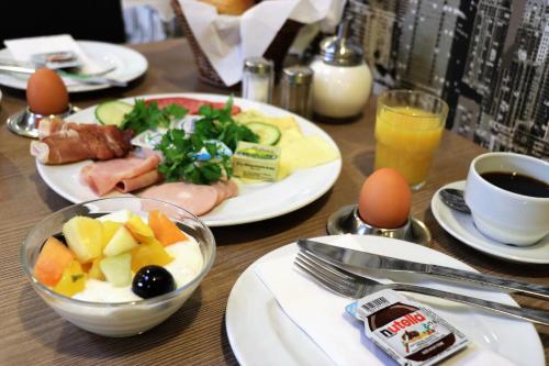 a wooden table topped with plates of food and eggs at Novum Hotel Holstenwall Hamburg Neustadt in Hamburg