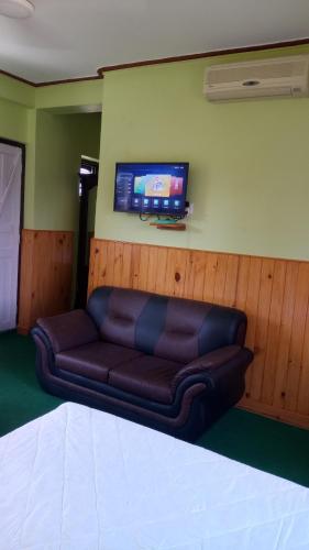 a couch in a room with a tv on the wall at New Pokhara Lodge - Pokhara Lakeside in Pokhara