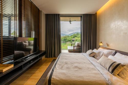 een slaapkamer met een groot bed en een flatscreen-tv bij 2 Bedroom Luxury Pool Penthouse at ATTA in Pak Chong