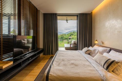 una camera da letto con un letto grande e una TV a schermo piatto di 2 Bedroom Luxury Pool Penthouse at ATTA a Pak Chong