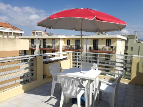 a white table and chairs with an umbrella on a balcony at Gardenia Casa Vacanze in Alghero