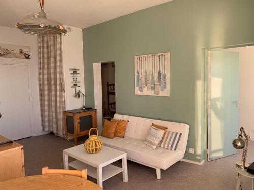 a living room with a white couch and a table at Le COURLIS vue panoramique sur la mer, balcons in Ault