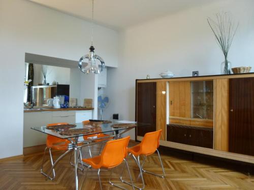 eine Küche mit einem Glastisch und orangefarbenen Stühlen in der Unterkunft Apartments Maximillian in Wien