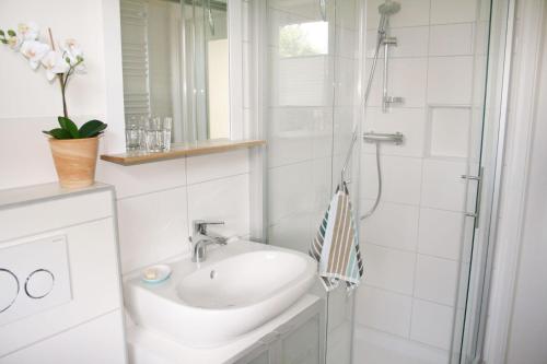 a white bathroom with a sink and a shower at Himmelreich Amrum in Norddorf