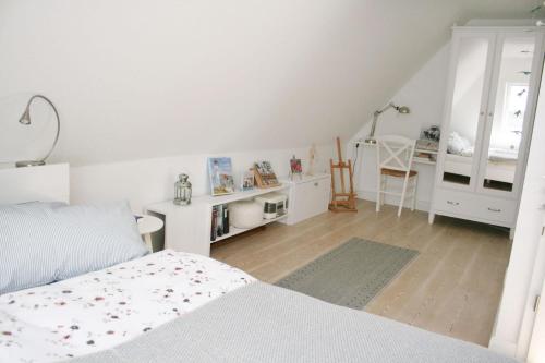 a white bedroom with a bed and a desk at Himmelreich Amrum in Norddorf