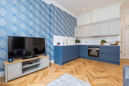 a kitchen with blue and white cabinets and a flat screen tv at Luxury Renovated 1 Bed Nr St James - Super Central in Edinburgh