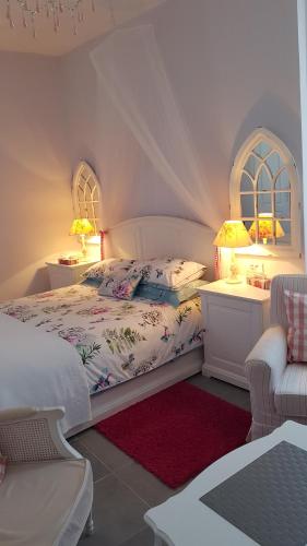 a white bedroom with a bed and two windows at Moulin de Cot in Clermont-lʼHérault