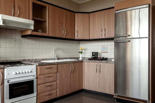 a kitchen with wooden cabinets and a stainless steel refrigerator at Lahoya Homes in Beirut