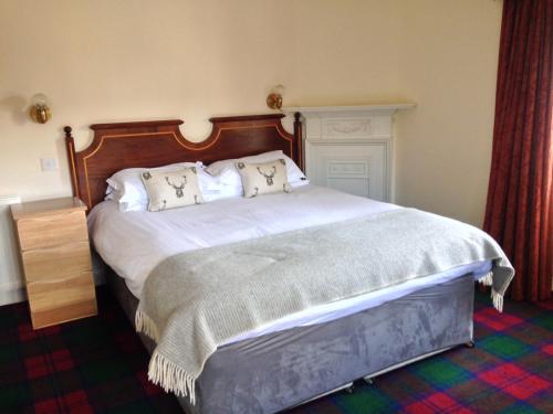 - une chambre dotée d'un grand lit avec des draps et des oreillers blancs dans l'établissement Highlander Inn, à Craigellachie