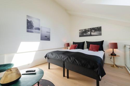 a bedroom with a bed with black sheets and red pillows at Nordic Host - Tollbugata 13 in Oslo