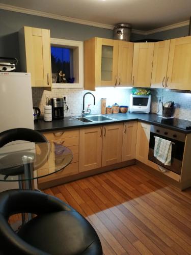 a kitchen with wooden cabinets and a sink and a table at Seaview apartment Karmøy in Sæveland